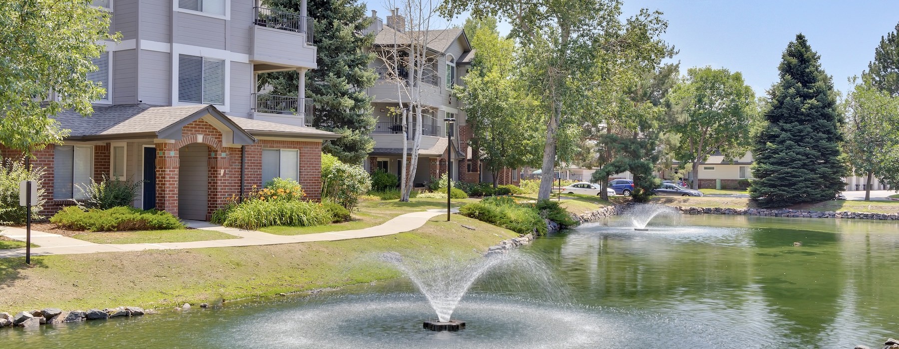 a water fountain in front of a building with trees