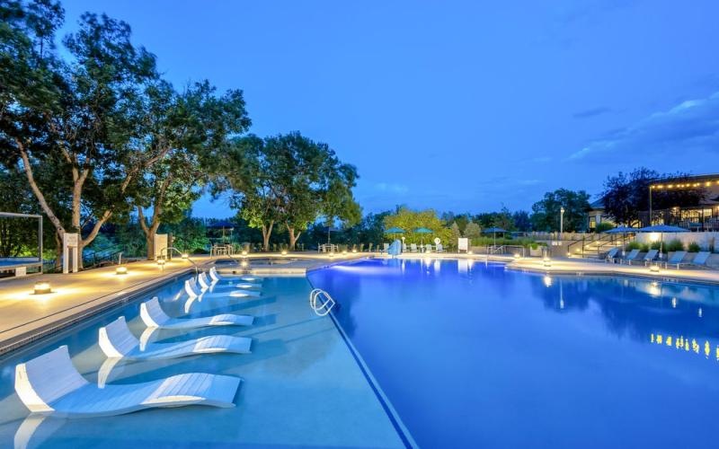 a swimming pool with trees and a building in the background